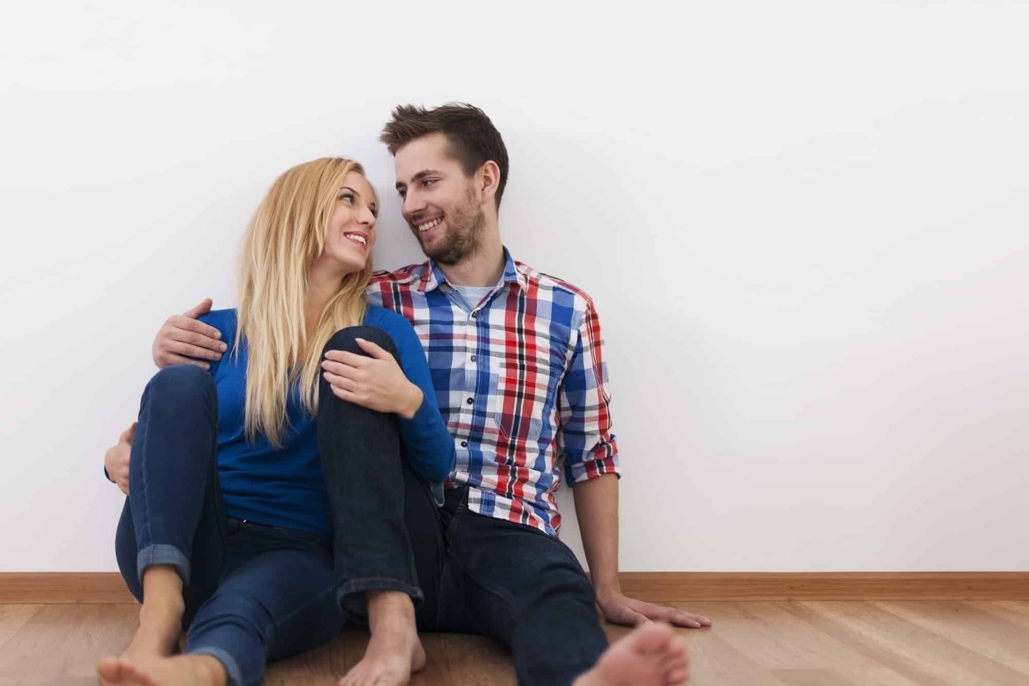 Flirting couple sitting on hardwood floor